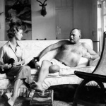 <p><b>Clifford Coffin</b>, <i>American writer Ernest Hemingway, with bare torso, reclining on a couch, holding a glass and petting a cat, with model Jean Patchett, sitting next to him with a cat on her lap, wearing a silk shirt and wrap skirt by B.H. Wragge, at Hemingway’s farmhouse, Finca Vigia, in Cuba</i>, 1950</p>