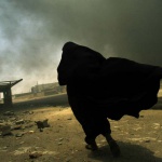 <p><b>Lynsey Addario</b>, 2003. An Iraqi woman walks through a plume of smoke rising from a massive fire at a liquid gas factory as she searches for her husband in the vicinity of the fire in Basra, Iraq, May 26, 2003.  The fire was allegedly started by looters picking through the factory, and residents in the vicinity feared the explosion of the four liquid gas tanks on the premisis...</p>