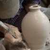 Removing clay from the foot of a bottle while throwing
