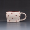White cup with heart pattern by Juliana Pequignot